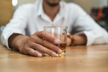 Close up glass of whisky in alcoholic man hand.