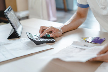 Close up person calculating monthly expense and credit card debt.