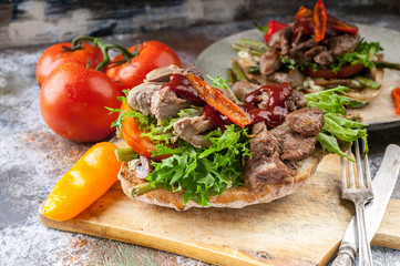 Sandwich with turkey meat, sweet peppers, tomatoes and greens on the grill.