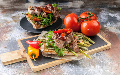 Mediterranean Kitchen. Grilled turkey meat on a traditional chabbata with sweet peppers, tomatoes and herbs on a cutting board.