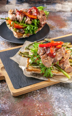 Mediterranean Kitchen. Vertical shot. Grilled turkey meat on a traditional chabbata with sweet peppers, tomatoes and herbs on a cutting board.