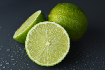 Fresh ripe limes on a dark background with water drop