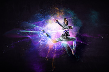 Modern female dancer jumping in hoodie with colourful splashes background. Mixed media