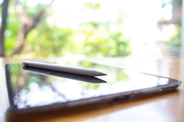 Apple pencil  with Reflecting Black tablet iPad Pro 10.5 inch on wood table, Bokeh green garden background, Perspective view, Close up shot, Selective focus, Technology, Business concept