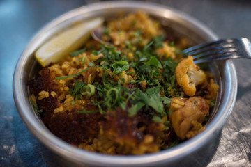 Close up of paella dish in metal bowl with fork