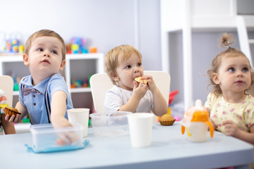 babies children eating healthy food in nursery or kindergarten