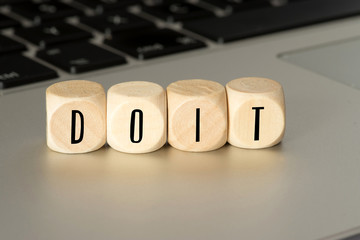 Ein Computer und Holzwürfel mit dem Slogan Do It