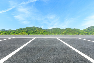 Parking lot pavement and green mountains natural landscape under the blue sky