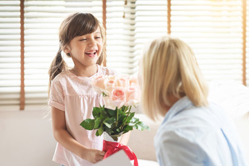 Daughter giving a bouquet of pink roses to her mom.