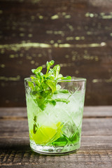 Summer old fashioned beverage with melon liqueur and mint leaves. Selective focus. Shallow depth of field.