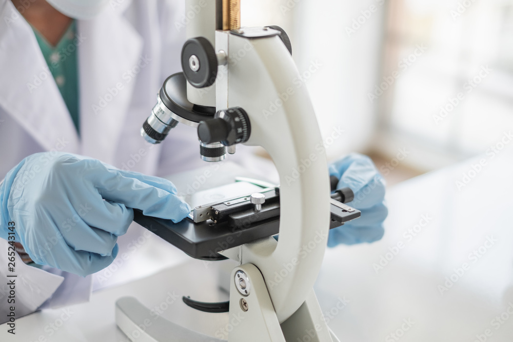 Wall mural a scientist hands working in laboratory with test tube microscope and solutions.