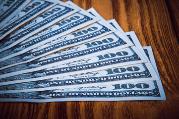 Dollar banknotes in fan at wooden background.