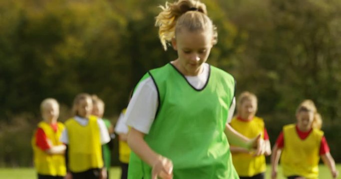 4K British girls' soccer team showing motivation & concentration at training session. Slow motion.