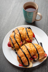 fresh croissant on the table, with hot tea, strawberries and bananas, delicious breakfast