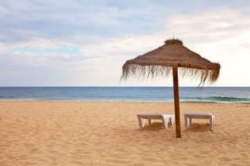 Beautiful sandy deserted beach with an umbrella and deck chairs on the beach. The concept of a summer holiday. Natural sea background