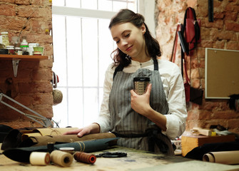 young woman works in a bag making studio, cuts out details