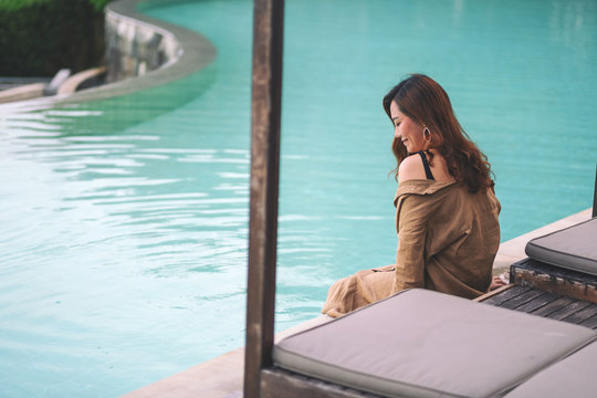 Portrait image of a beautiful asian woman enjoyed sitting by the swimming pool