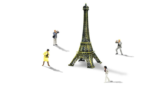 Vacation and Holiday Trip Concept : Miniature figurine character as travelers taking photograph Eiffel Tower model isolated on white background.