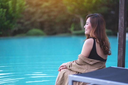 Portrait image of a beautiful asian woman enjoyed sitting by the swimming pool
