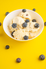 ice cream with blueberries, on a white background with a spoon. on a yellow background, summer mood