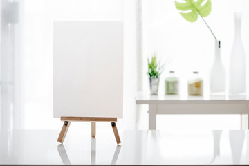 Mockup blank white menu on wooden stand on white table.
