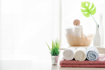 Mockup bath towel on white table with houseplant in white room, copy space for product display.