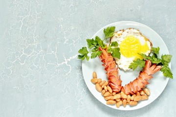 Creative breakfast with sausages and scrambled eggs. The theme of the tropics is sausages like palm trees, parsley, scrambled eggs like the sun, and white beans like stones on the beach. 