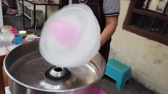Hand rolling cotton candy in candy floss machine