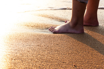 Girl's bare feet standing on the sand of beach.