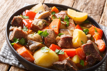 Pork gravy with mushrooms and vegetables close-up on a plate. horizontal