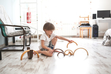 Caucasian Boy playing with wooden rainbow on floor