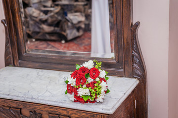 Luxurious wedding bouquet of red roses with wedding rings in a box on a marble slab. Close-up.