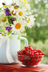A bouquet of wildflowers and a glass bowl of red currant