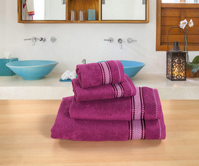 FOUR PIECE OF PURPLE COTTON TOWEL SET ON BROWN SURFACE