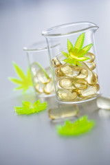 Pillen, Tabletten, Kapseln mit Cannabis Marihuana Hanf und CBD in Labor Becherglas gegen Schmerzen zur Therapie als Medizin 