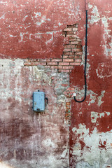 Dirty destroyed brick wall with some paint and electrical equipment. Conceptual background.