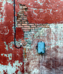 Dirty destroyed brick wall with some paint and electrical equipment. Conceptual background.