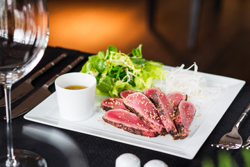 Marinated tuna with lettuce and kunshut on a white plate