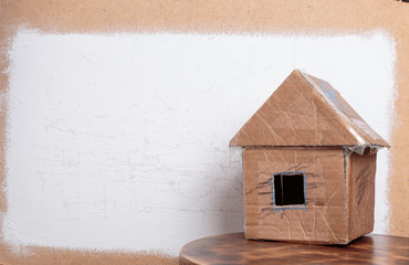 Handmade cardboard house on dirty white textured background.
