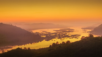 Fototapeta premium sunrise at Phu Huay Esan View Point, view of the hill around with sea of mist above Mekong river with red sun light in the sky background, Ban Muang, Sang Khom District, Nong Khai, Thailand.
