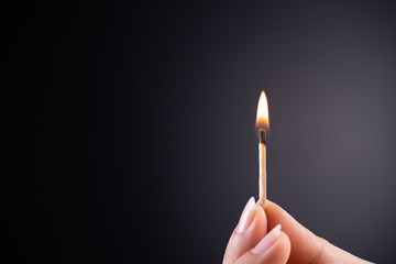 Close up woman hand holding a burning match.