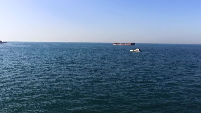 Aerial view of beautiful seascape with white yacht and dark barge on blue sky background. Stock. Beautiful calm sea in a sunny day with two floating vessels.