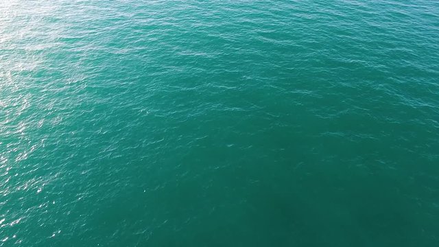 Aerial view of calm sea or ocean water surface, natural background. Stock. Top view of clean ocean water with sunflares.