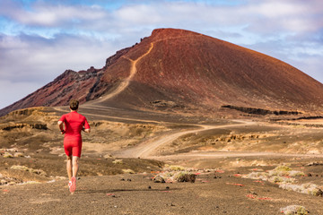 Sport and fitness athlete running on mountain trail, man active lifestyle. Man runner on long distance run through desert summer landscape.