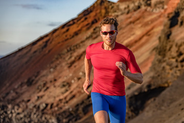 Fit runner man sport athlete trail, running outside on volcano mountain in desert. Motivation and...