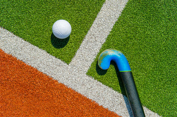 Field hockey stick and ball on brown and green grass