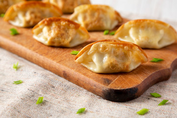 Homemade gyoza on a rustic wooden board, side view. Close-up.