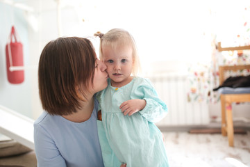 tender mom hugs her daughter blonde in bright room