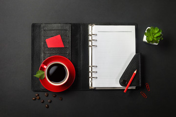 Black office desktop with notebook, credit card and red cup of coffee