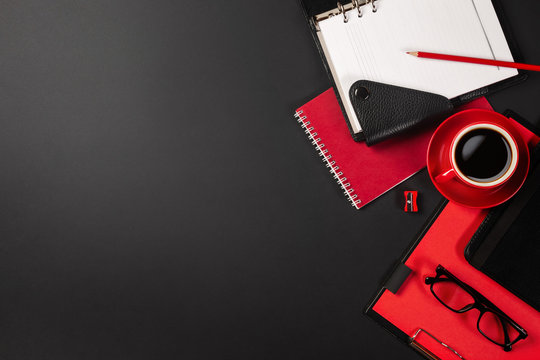 Office desk table with red cup of coffee and notebooks. Top view with copy space